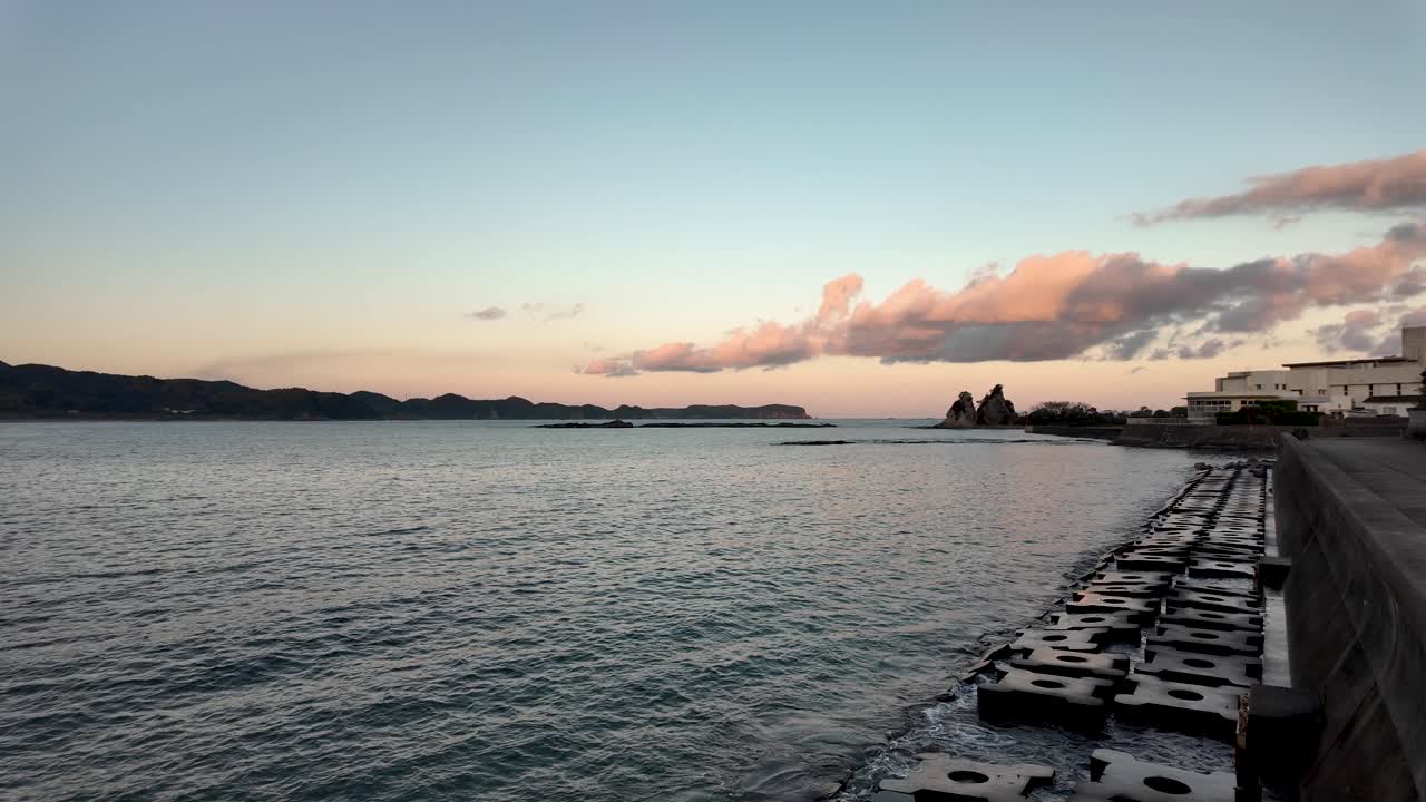Serene view of Nachi Bay with breakwater wall at golden hour sunset