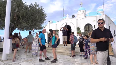 crowd of foreign tourists standing in front of greek church
