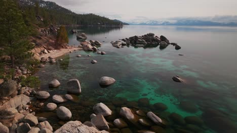 sunny winter day sand harbor south lake tahoe aerial drone california shoreline large boulder rocks incline village crystal clear glassy turquoise water secret whale chimney kings beach static shot