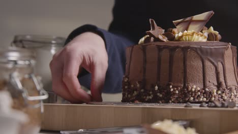 close up of man in kitchen at home with freshly baked and decorated chocolate celebration cake on work surface 1