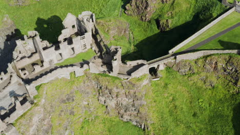 Architectural-Ancient-Ruins-of-Medieval-Dunluce-Castle-in-Ireland,-Overhead-Flying-View