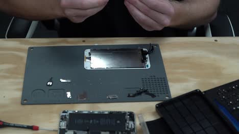 hombre reparando y atornillando la nueva pantalla del iphone de apple para repararla