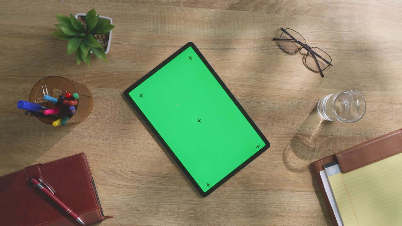 colocación plana de una tableta con pantalla verde y suministros de oficina en un escritorio de madera