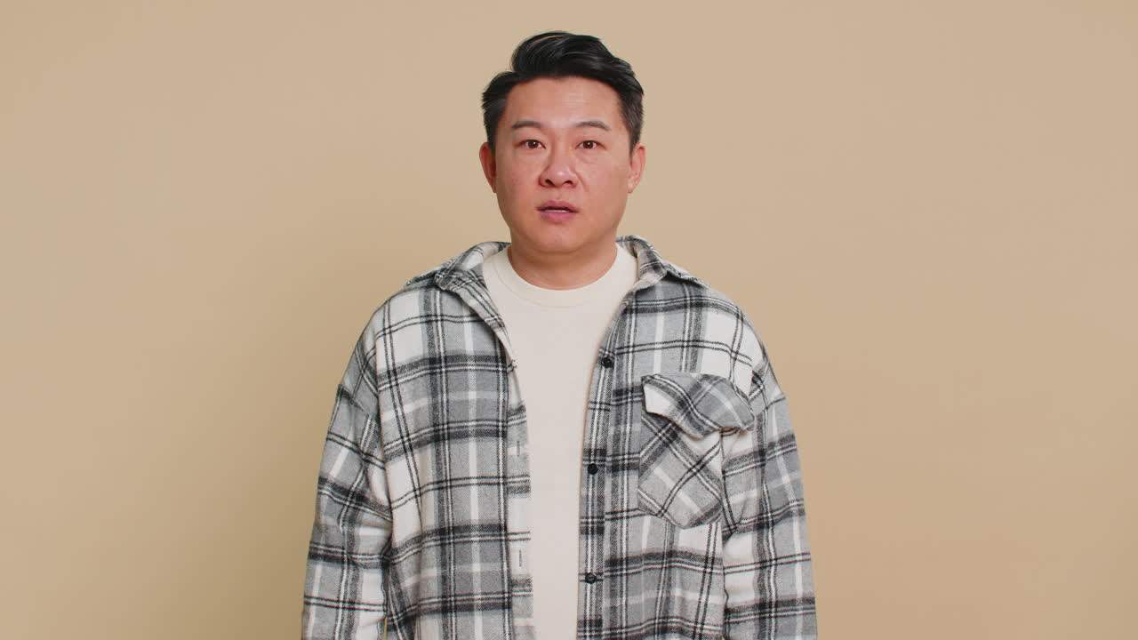 Confused excited asian man knocking door gesture asking who is at home feeling embarrassed no idea