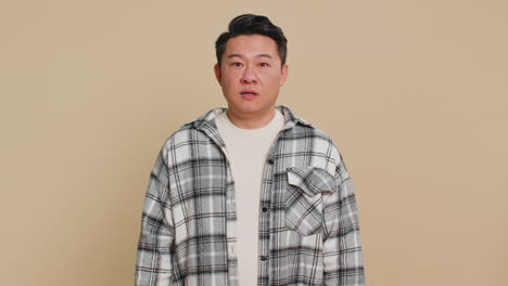 confused excited asian man knocking door gesture asking who is at home feeling embarrassed no idea