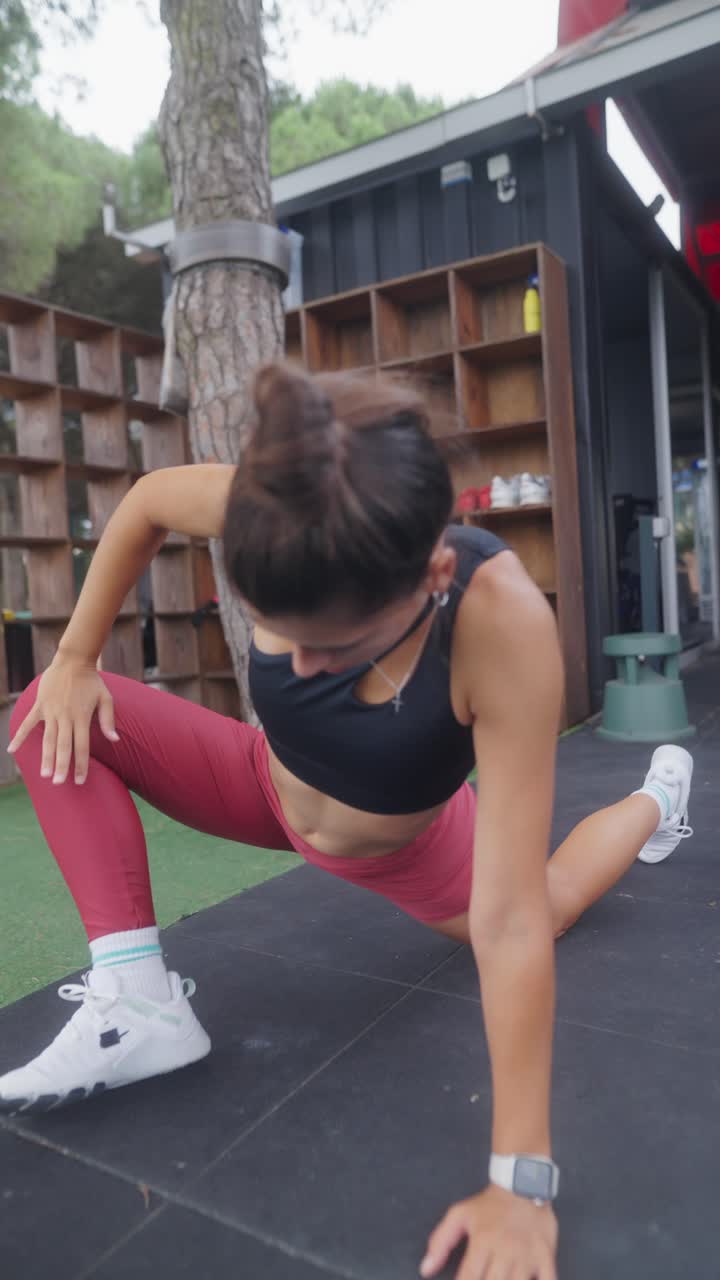 A woman performing stretches and exercises in an outdoor gym