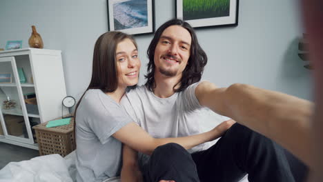 happy couple taking selfie in bedroom