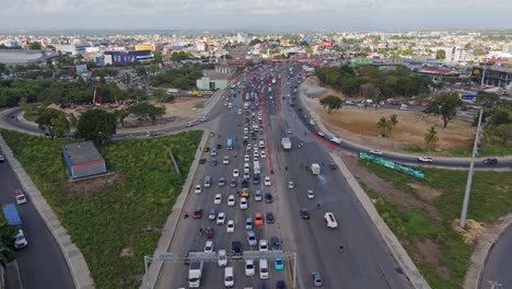 aerial birds eye shot of traffic jam scene on duarte highway in santo domingo. busy autopsie with palm trees and industrial companies. top down. sunset time on dominican republic.