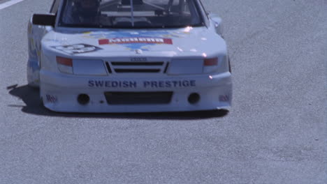 a white race car travels around a track