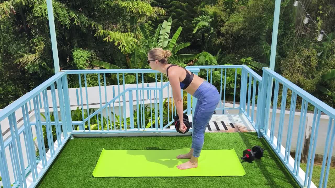 mujer trabajando con pesas en un balcón
