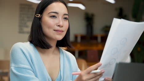 an business woman smiles while consulting working papers in a coffee shop