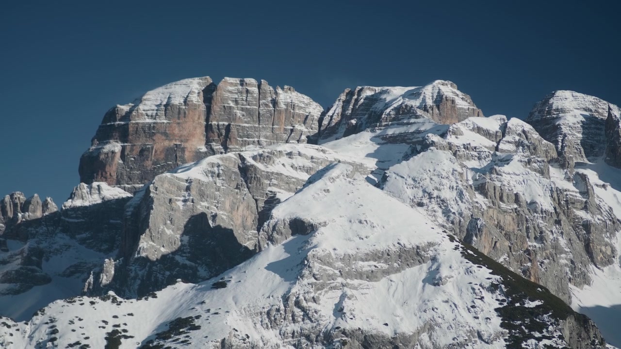 Cresta della vetta montuosa innevata, ripresa statica a mano libera. Vista panoramica ad alta quota di una maestosa cima alpina completamente coperta da neve bianca invernale