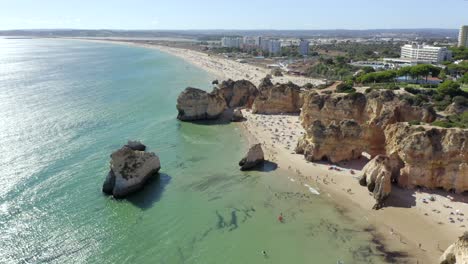 Fantastic-rock-formations-stick-out-of-incredible-Turquoise-ocean-waters-near-amazing-Cliffs-on-Portimao-Coastline-Drone-Aerial