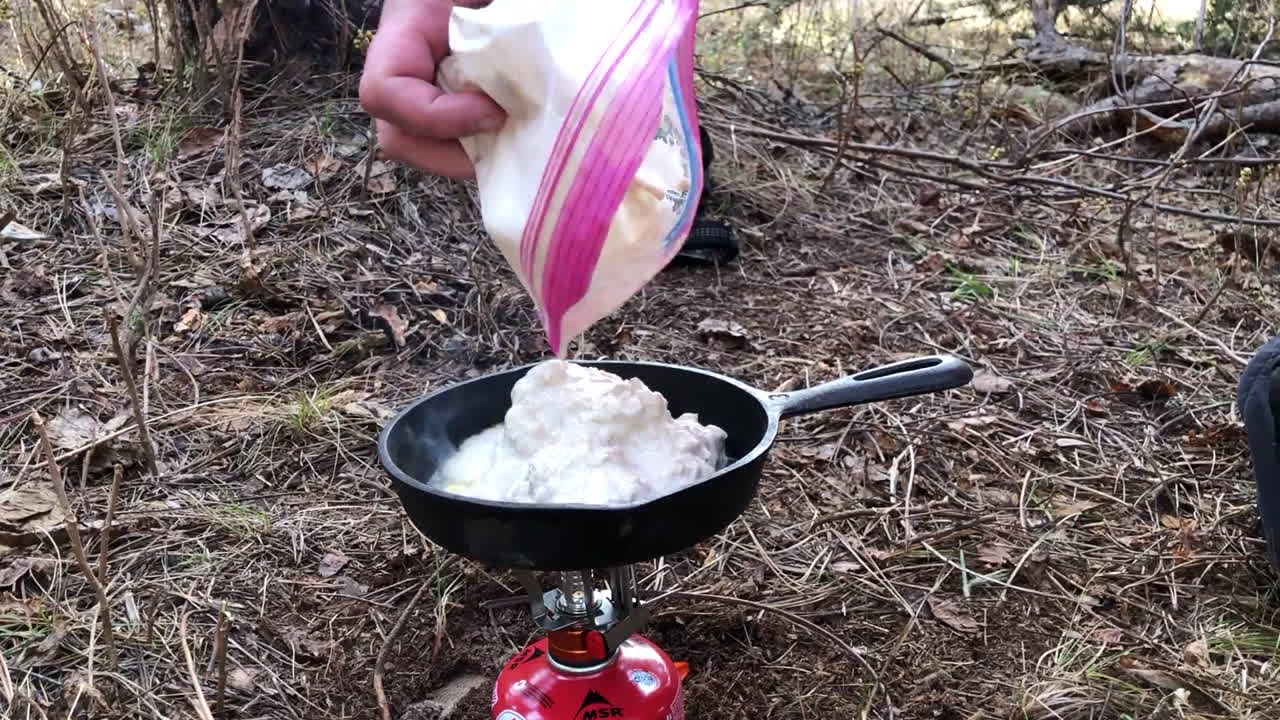 Cooking bannock with a cast iron pan over a small gas powered camping stove