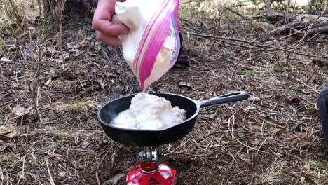 cooking bannock with a cast iron pan over a small gas powered camping stove