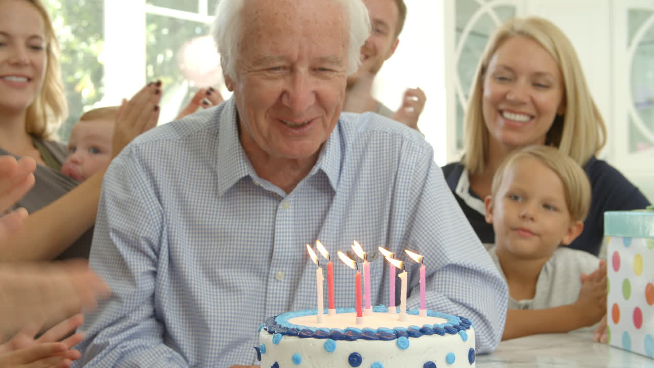 Ripresa al rallentatore del nonno che spegne le candeline sulla torta di compleanno