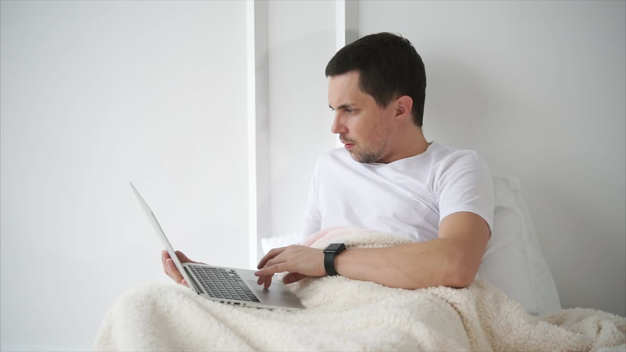 hombre trabajando en la computadora portátil en la cama