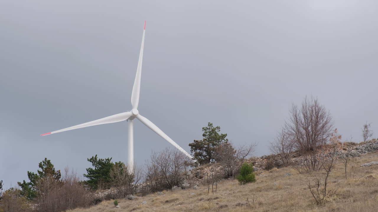 A large wind turbine plant. Sustainable and renewable green energy from the wind. Turbines arranged on a mountain plateau. Windy weather before the storm.