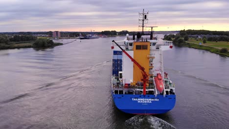 Barco-Panda-Con-Viento-De-Cola-Cruzando-El-Río-Oude-Maas-En-Un-Paisaje-Verde-De-Lado,-Países-Bajos