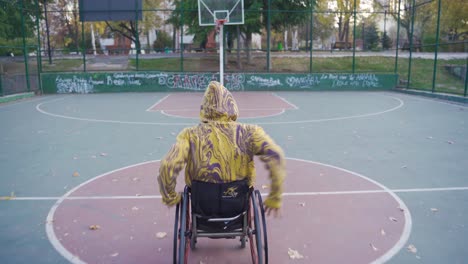 un joven discapacitado driblando en una cancha de baloncesto al aire libre.