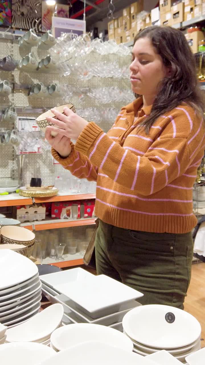 Young woman choosing soup bowls in a big store.