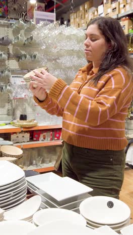 young woman choosing soup bowls in a big store.