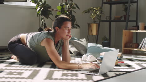 woman browsing the web on laptop on floor at home