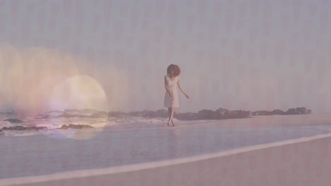 Animation-of-lens-flares-over-happy-biracial-young-woman-with-arms-outstretched-walking-at-shore