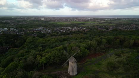 Bidston-Windmill-at-dawn,-aerial-drone-anti-clockwise-pan-and-inward-sunrise-reveal