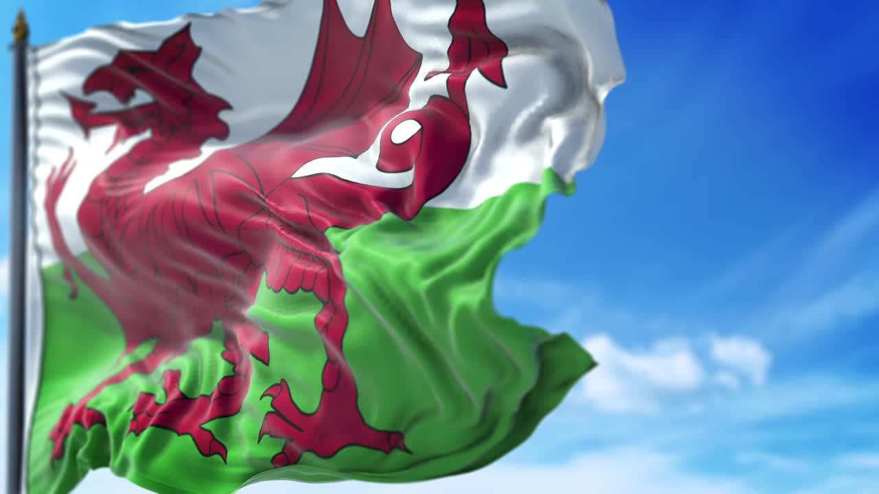 la bandera galesa está ondeando lentamente contra el cielo azul.
