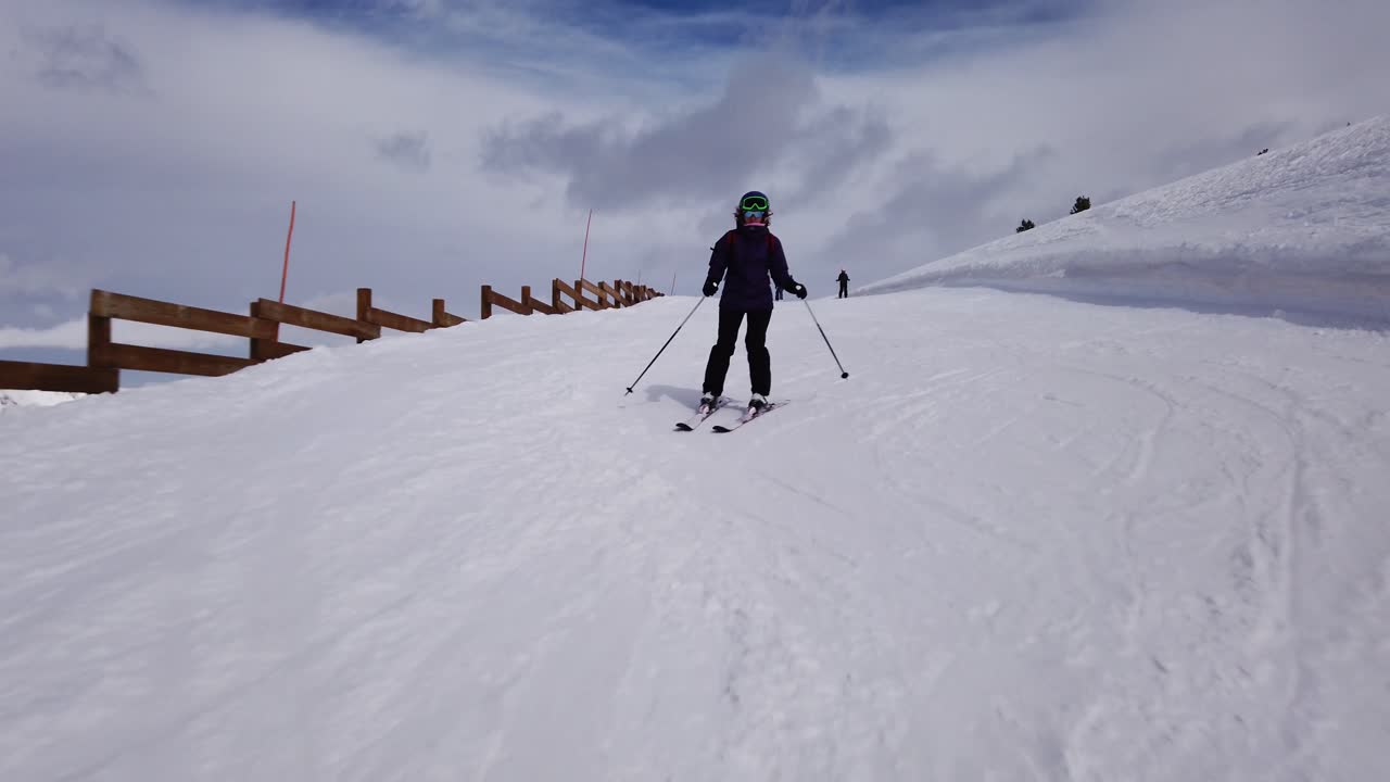 슬로프를 내려가는 여성 스키어를 따라 정면에서 촬영