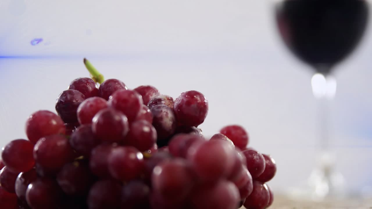 Bright blue light moving across causing lens flare and shifting camera focus from glass to grapes