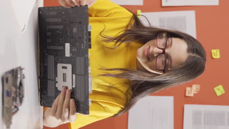 vídeo vertical de una niña inteligente mirando con curiosidad los materiales tecnológicos.