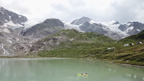 vuelo de drones sobre el lago y el glaciar stein con un hombre en un colchón de aire en los alpes de urner en suiza