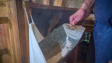 el hombre sacude su harina de su pala en una bolsa