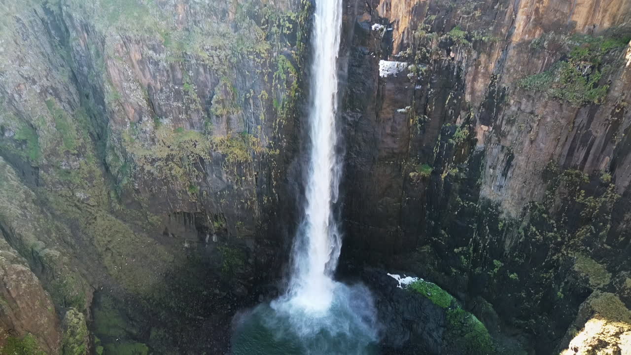 Vista aérea de drone das Cataratas Maletsunyane caindo em um cânion profundo nas terras altas do Lesoto, cercadas por penhascos acidentados e vastas paisagens montanhosas