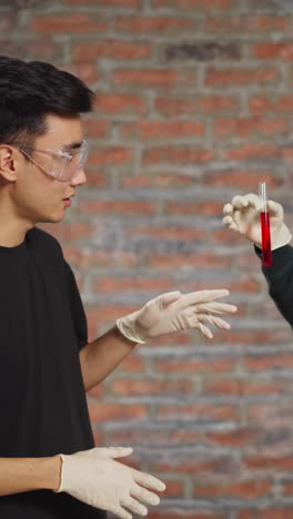 young asian scientist discusses red inorganic material states and test results with african-american colleague working together in laboratory