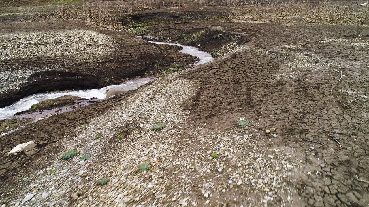 Dry Streambed with Water Flowing Through Cracked Earth