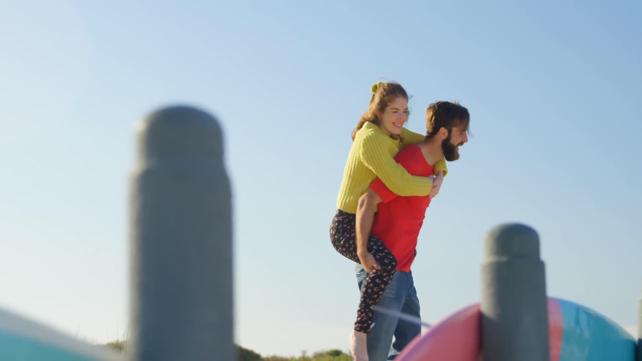 Man giving piggyback ride to woman on beach 4k