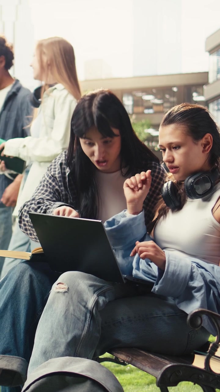 Vertical Video Students discussing notes beside laptop on campus bench
