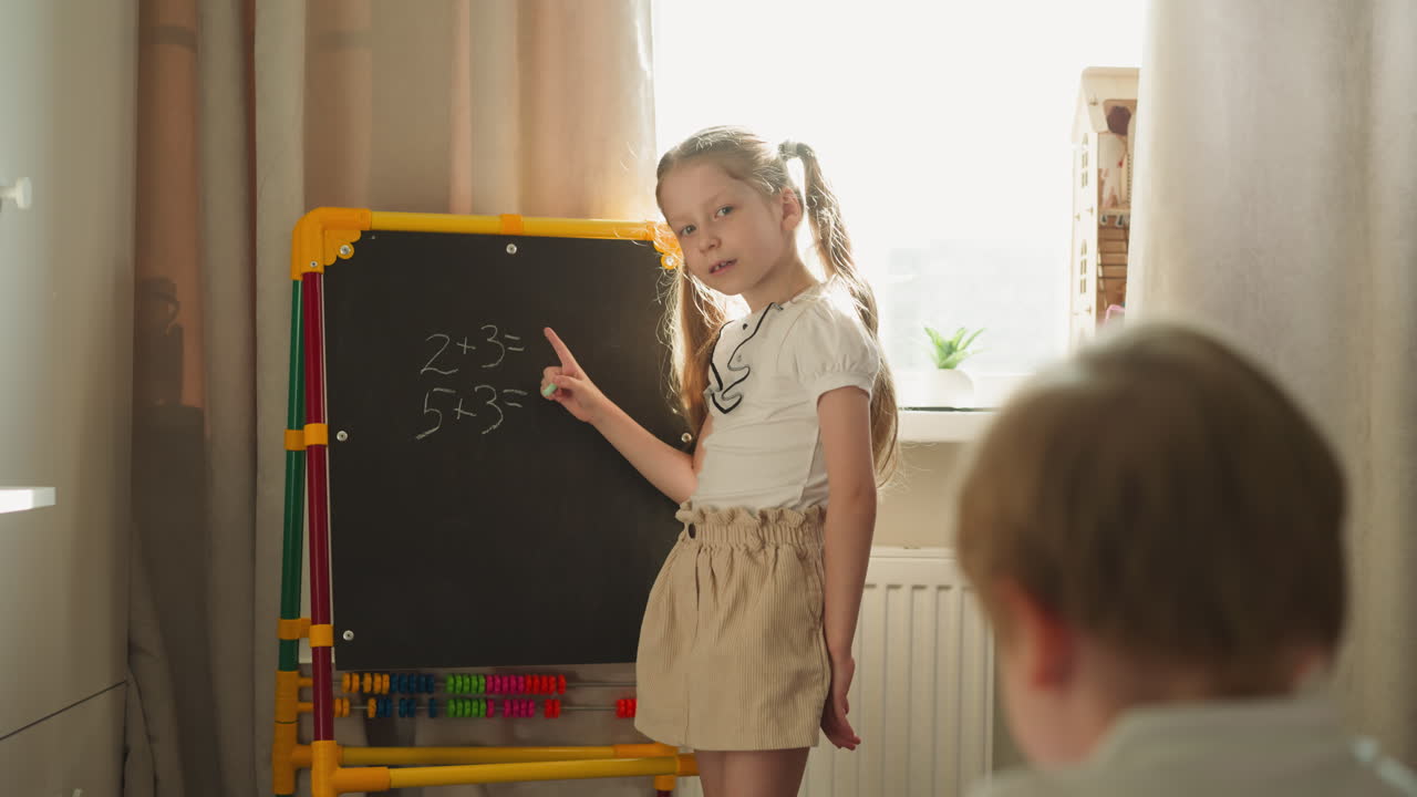 девочка объясняет мальчику математику, указывая на доску.
