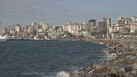 view of waves breaking on reefs and rocks with cityscape, 4k uhd