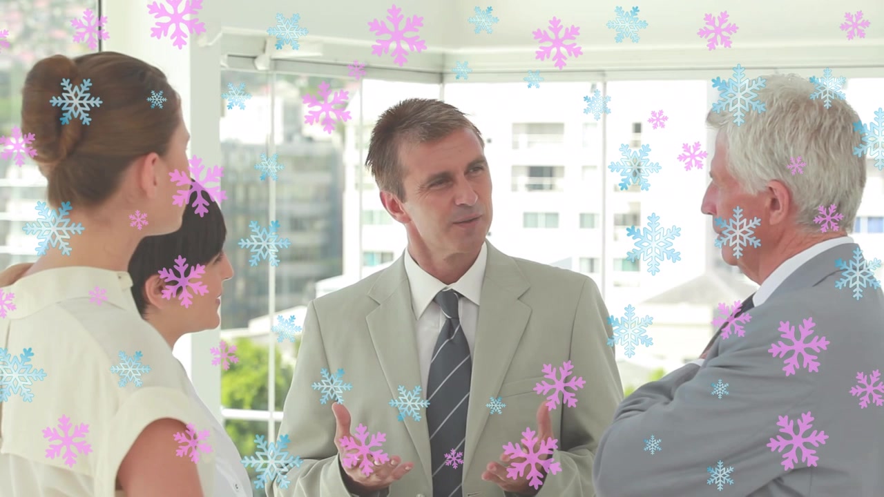 Ícones de flocos de neve rosa e azuis flutuando sobre diversos profissionais discutindo juntos no escritório.