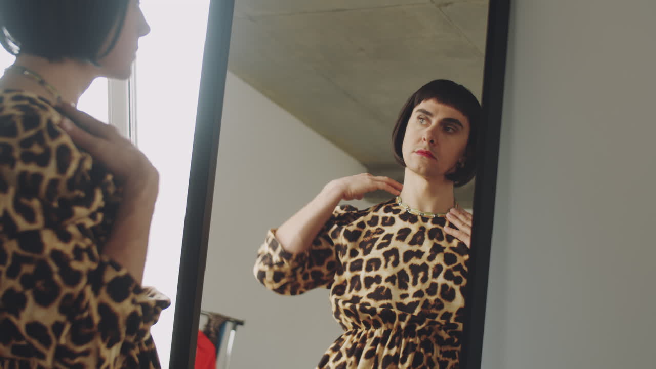 Uomo transgender in abiti femminili che si guarda allo specchio