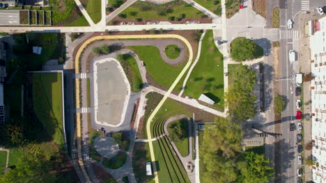 Vista-Panorámica-Aérea-Sobre-El-Paisaje-Urbano,-Los-Vehículos-Circulando-Y-El-Jardín-Público