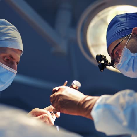 neurosurgeon in special surgery glasses provides operation. assistand helps medic. careful attentive doctor in operating room. closeup