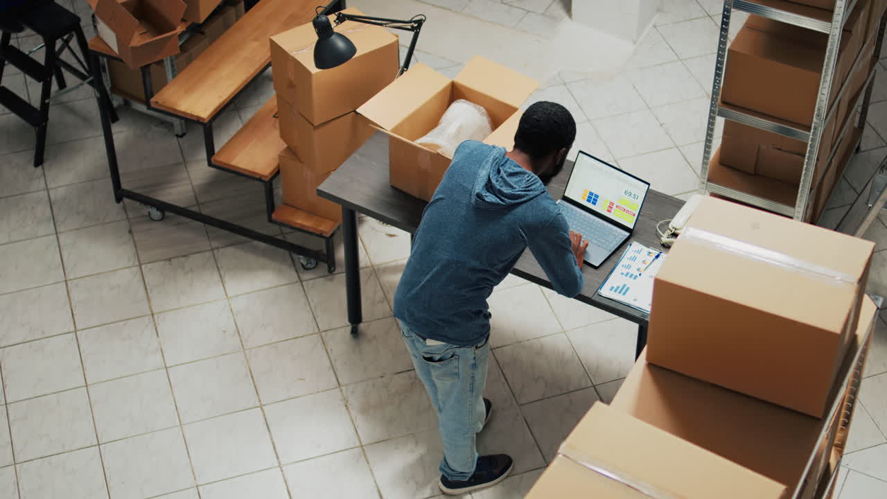 Man Working in Warehouse with Laptop and Boxes