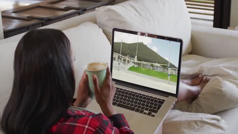 composite of woman sitting at home holding coffee watching athletics high jump event on laptop