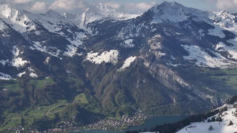 Snow-covered-mountains-aerial-view-with-lush-and-lake-at-Glarus,-Switzerland