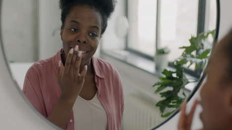 woman applying skincare in bathroom mirror